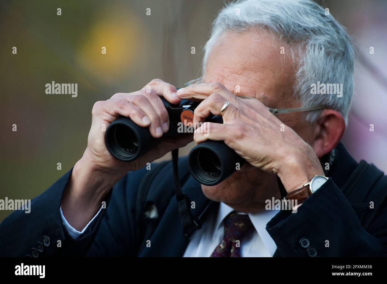 Well dressed elderly businessman in suit and tie birding with binoculars Stock Photo
