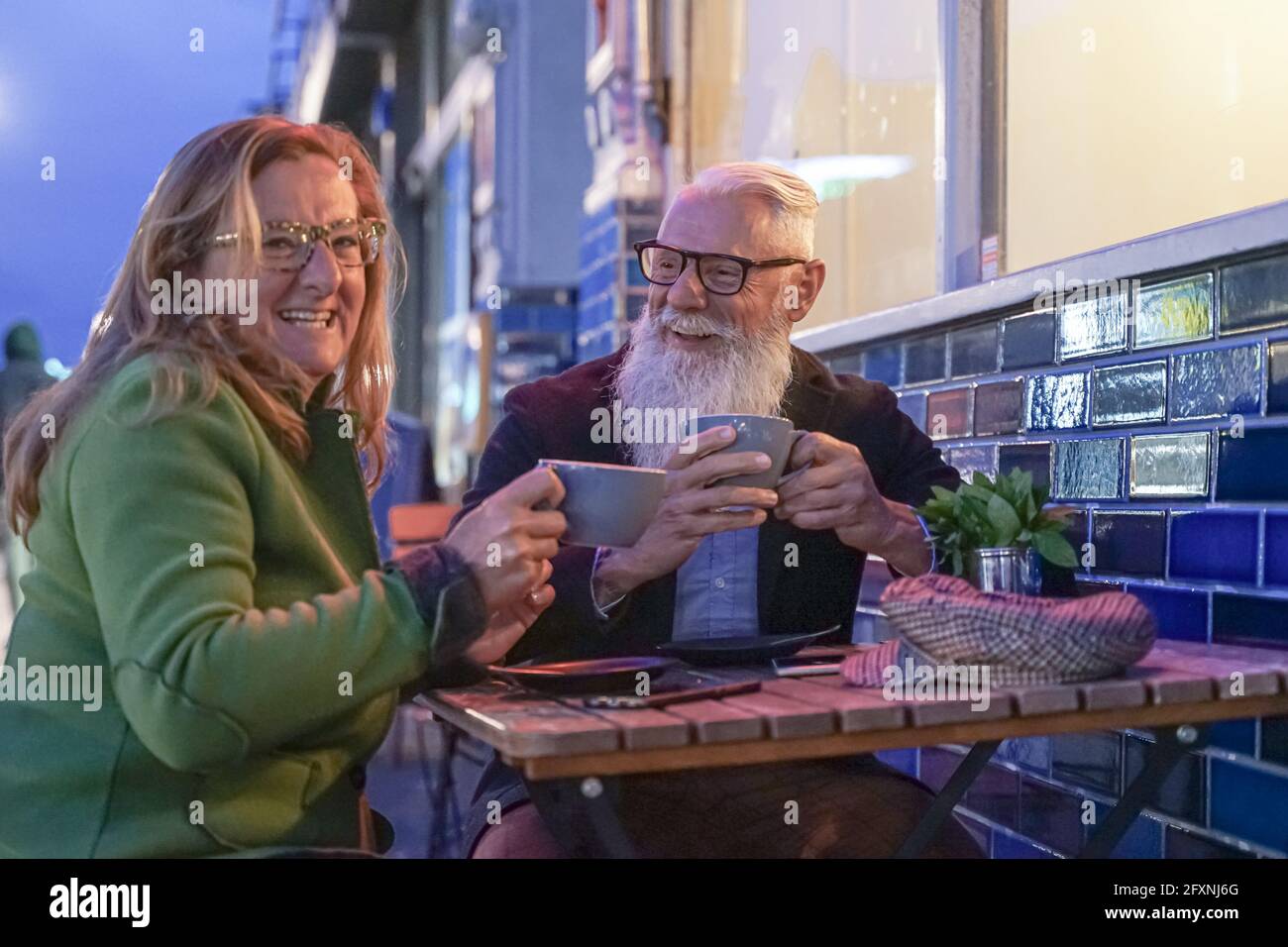 Senior couple having fun drinking at coffee bar on traveling. Mature man and woman wife on active elderly vacation. Happy retirement concept with reti Stock Photo