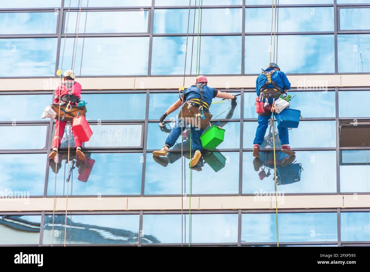 Industrial climbers cleaning the exterior facade of the rear glass of a skyscraper Stock Photo