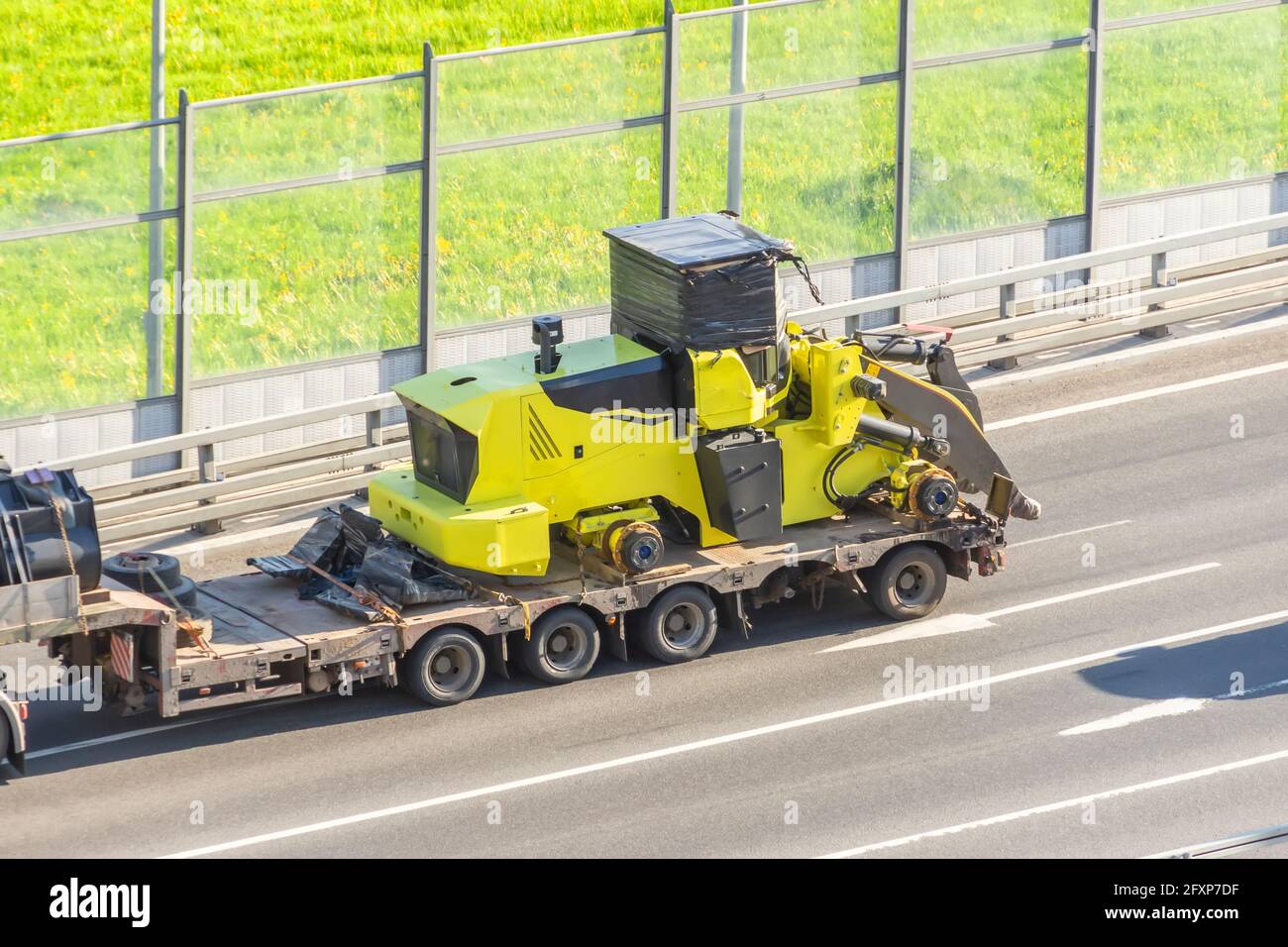 Truck with a long trailer platform for transporting heavy machinery, loaded tractor without