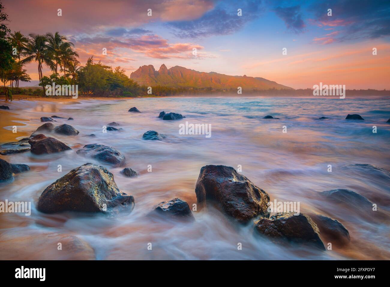 Sunrise over the calm bay waters at Anahola Beach Park, Kalalea mountain in the distance, Hawaii, United States of America, North America Stock Photo