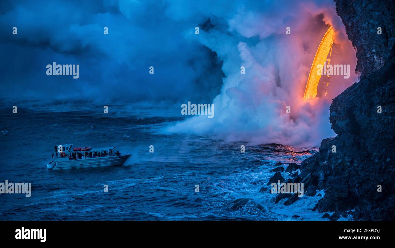 A tour boat observes lava pouring into the sea, Hawaii Volcanoes National Park, UNESCO, Hawaii, USA, Pacific Stock Photo