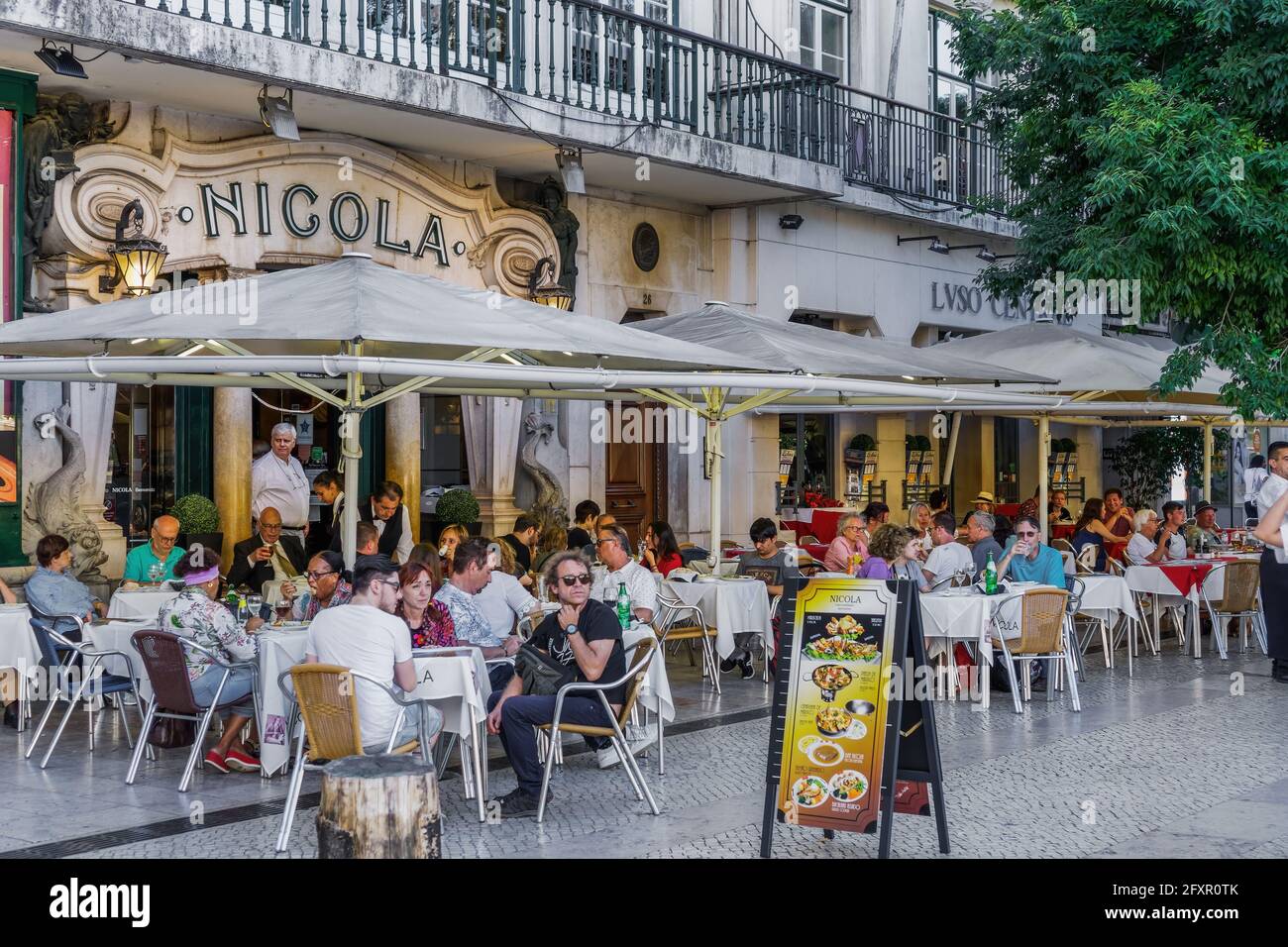 Historic Cafe Nicola entrance with art deco facade and seated customers at outdoor tables in Rossio Square, Lisbon, Portugal, Europe Stock Photo