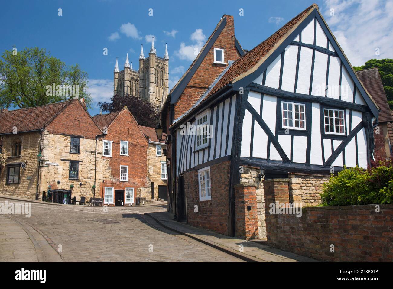 View up cobbled Michaelgate to Lincoln Cathedral, crooked half-timbered house in foreground, Lincoln, Lincolnshire, England, United Kingdom, Europe Stock Photo