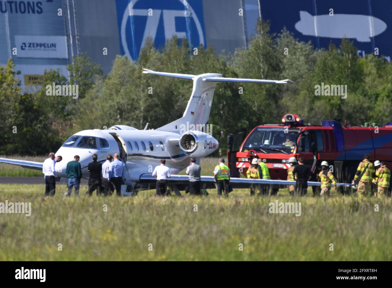 Friedrichshafen, Germany. 27th May, 2021. Firefighters and an airport fire engine stand next to an emergency landing passenger jet. Credit: Felix Kästle/dpa/Alamy Live News Stock Photo