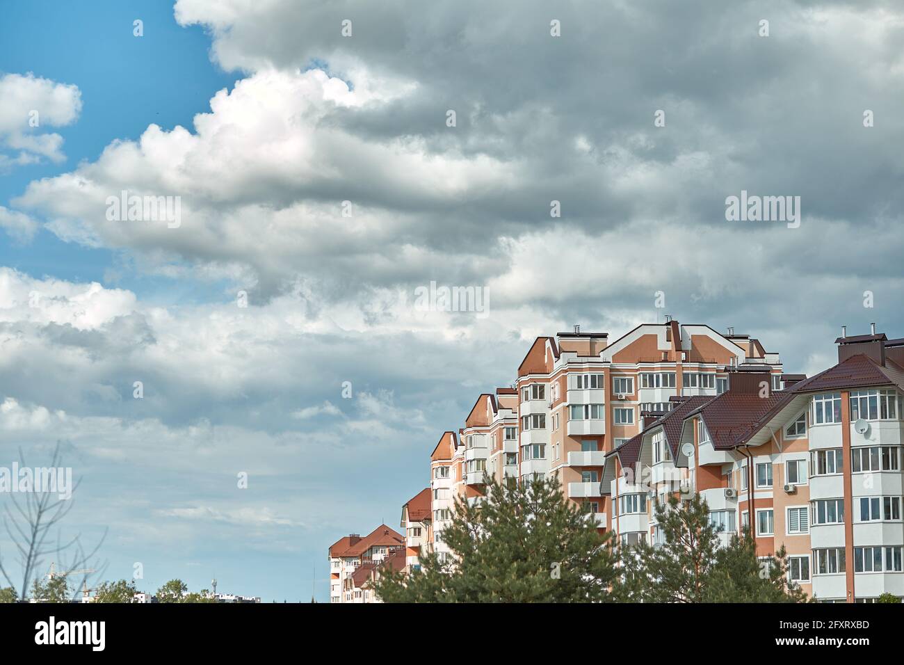 Residential modern multi-story houses in front of cloudy after rain blue sky. Evening city view. Copy space. The concept of renting out apartments Stock Photo