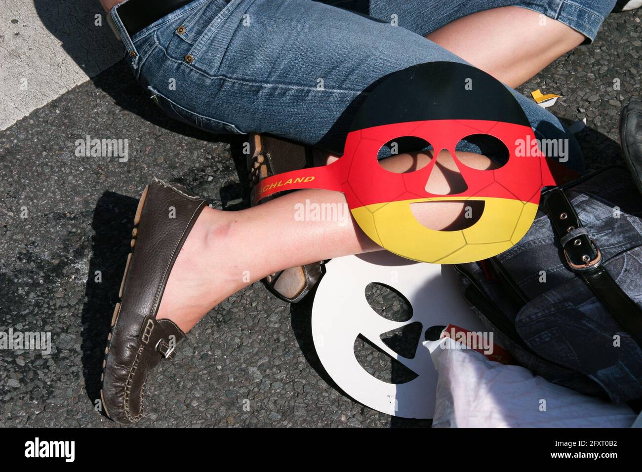 A face mask in black, red and gold lies on the knee of a participant who is sitting on the floor. Stock Photo