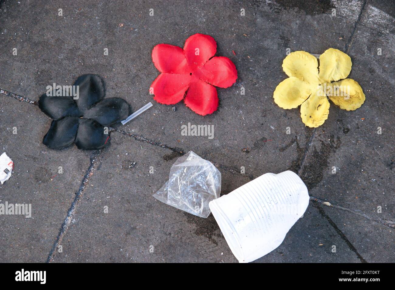Three plastic flowers in black, red and gold lie on the floor between plastic pans Stock Photo