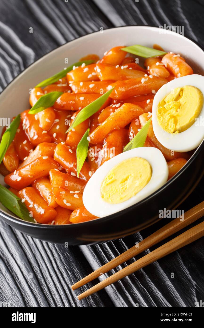Korean tteokbokki spicy rice cake with eggs close-up in a bowl on the table. Vertical Stock Photo