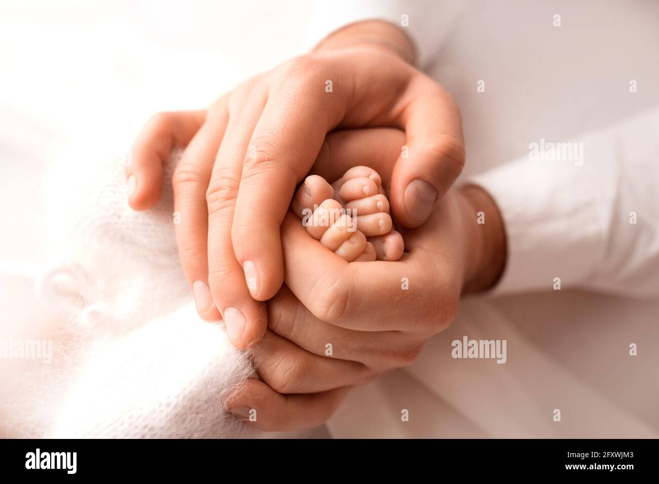 Children's feet in hold hands of mother and father. Mother, father and Child. Happy Family people concept. Stock Photo