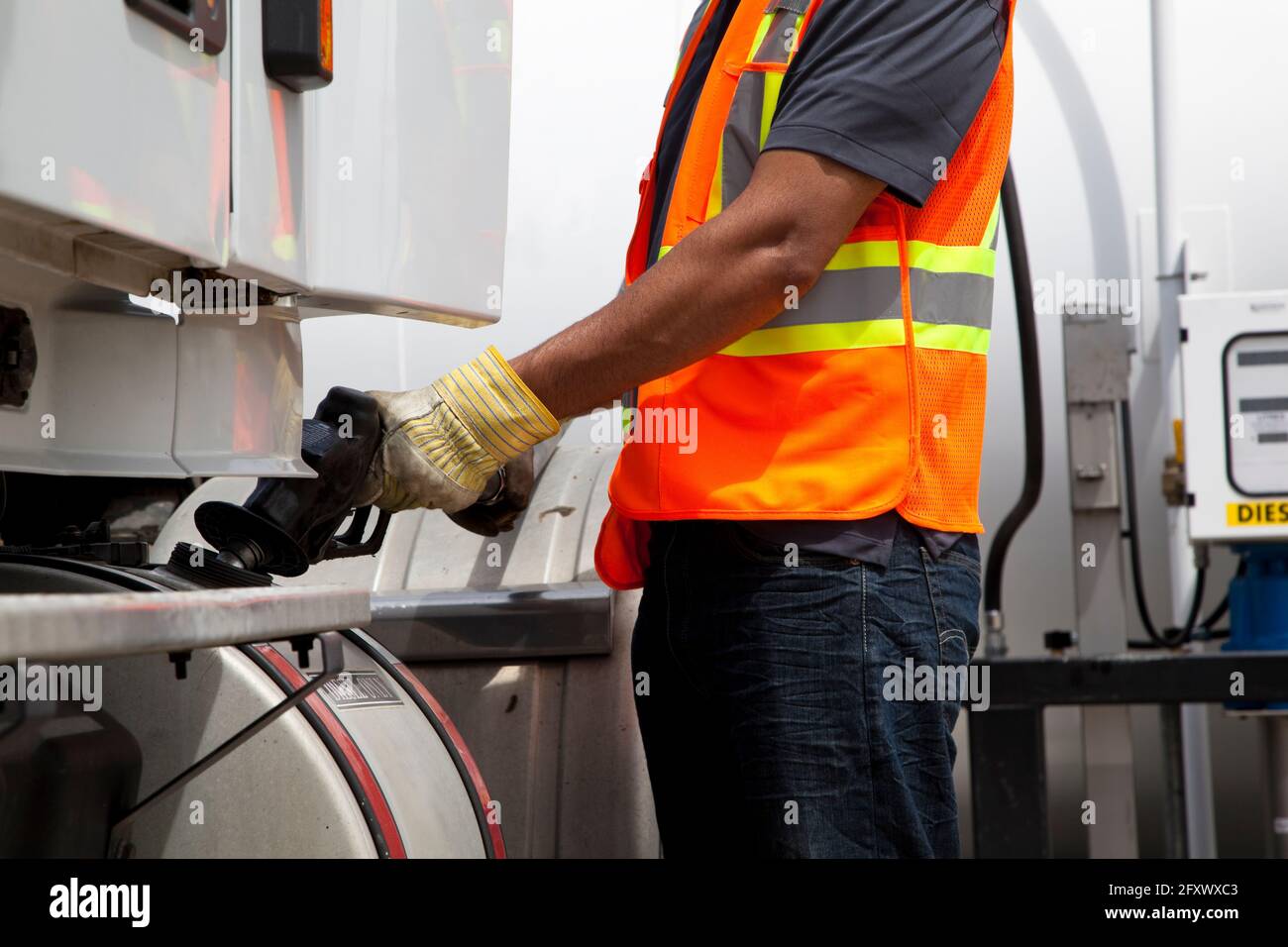 Truck driver refuelling transport truck wearing safety vest Stock Photo