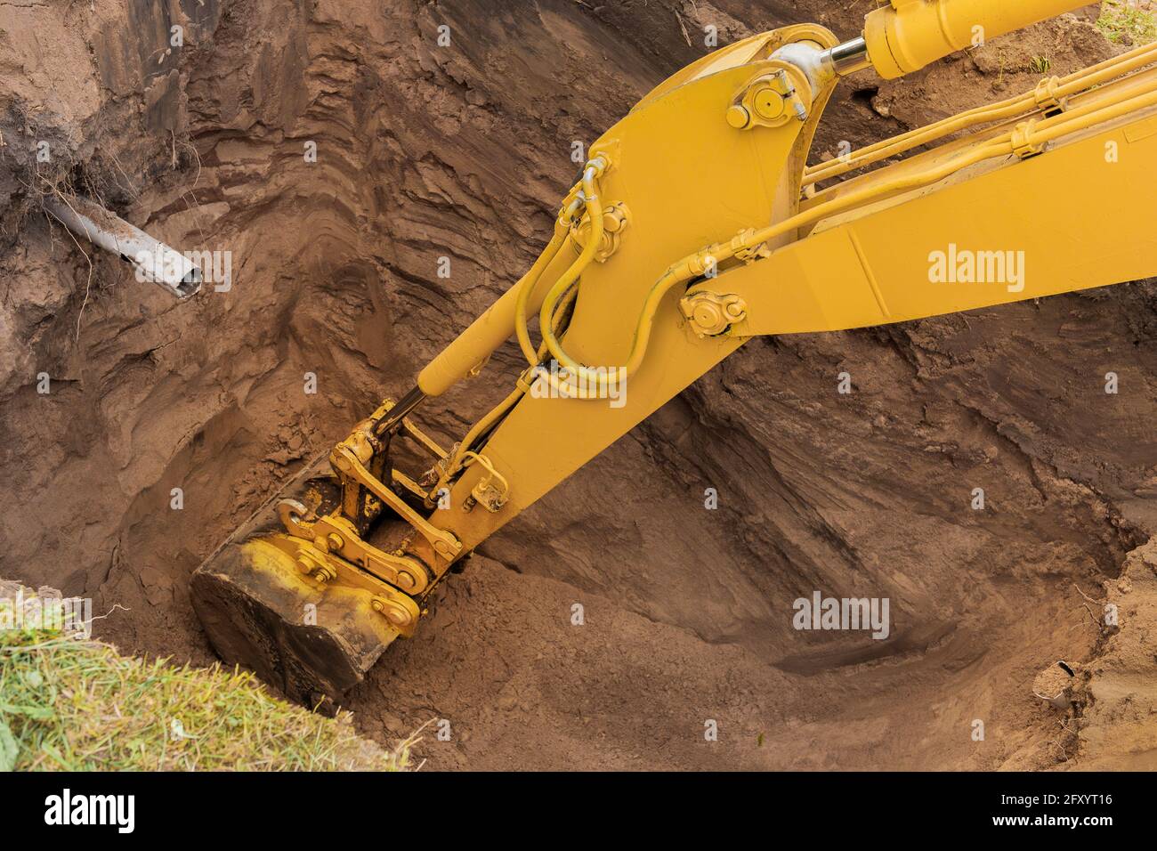 The hydraulic piston of the excavator bucket with the ground digs a