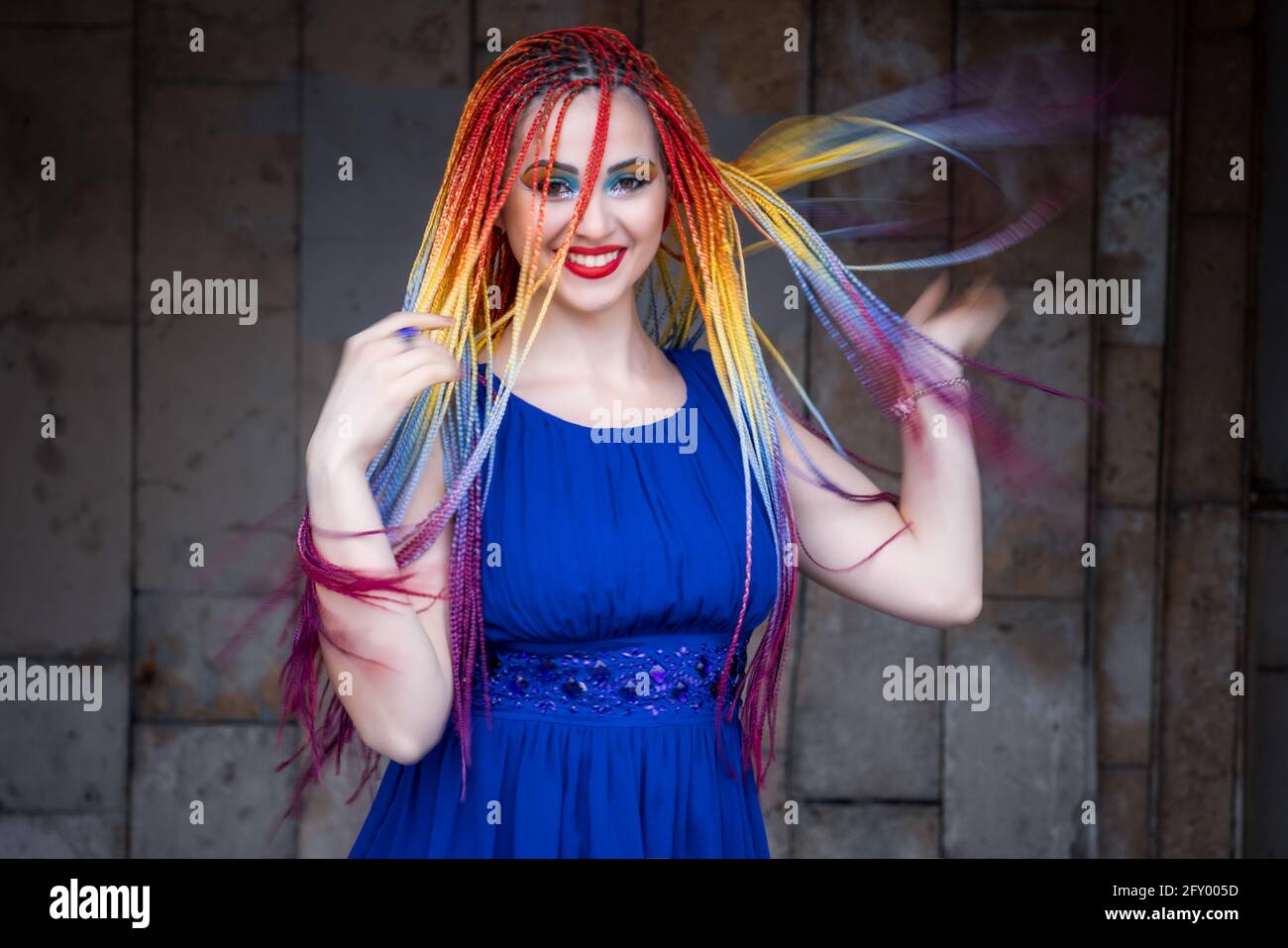 A beautiful girl in a bright blue dress with rainbow African braids and  unusual glitter makeup. Spins and laughs against the background of an old  larg Stock Photo - Alamy