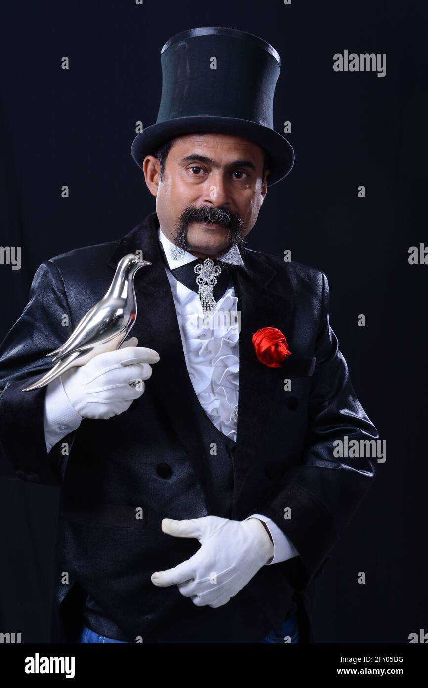 magician in suit and hat standing with crossed arms in dark smoky room