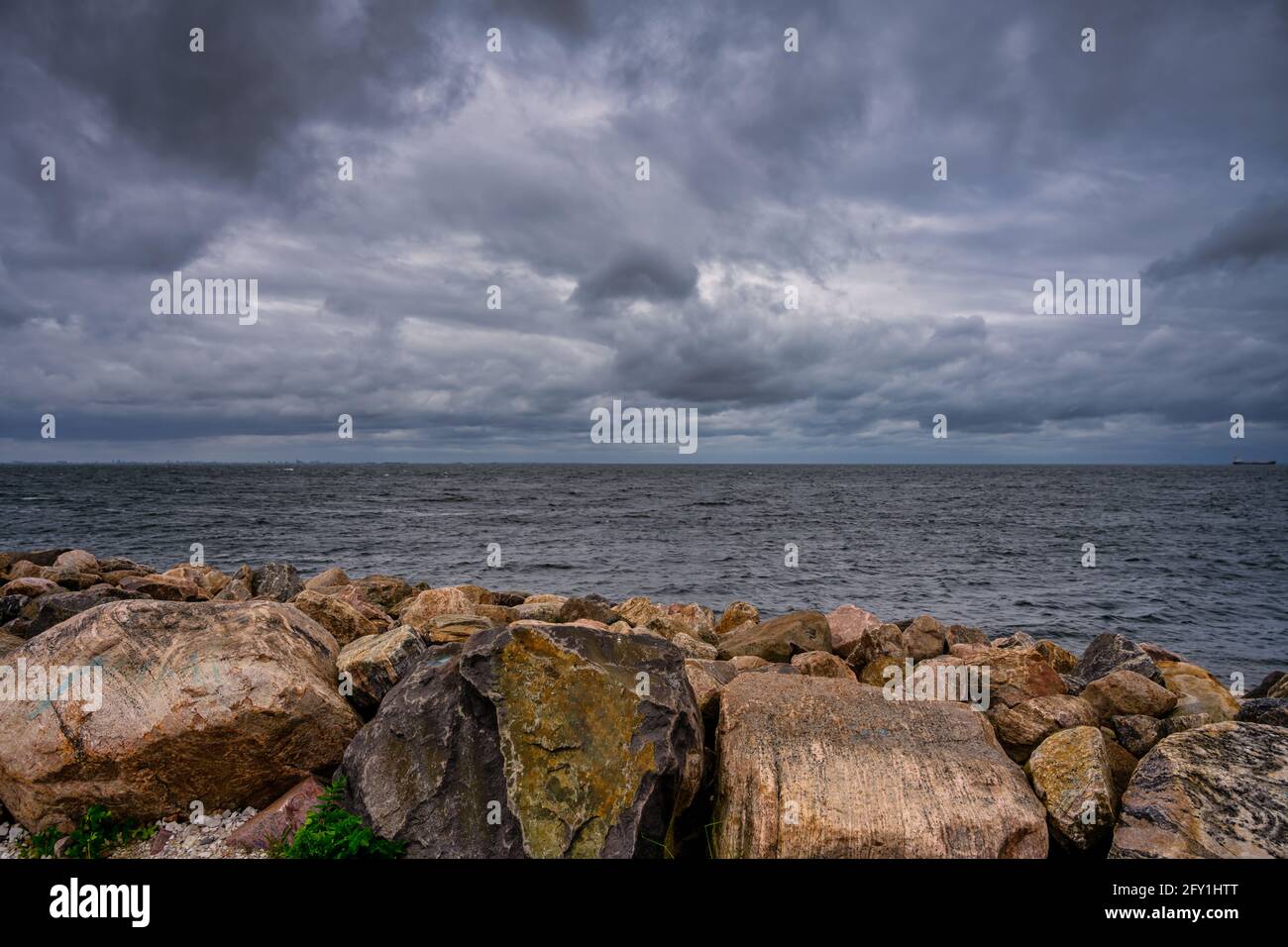 A beautiful, dramatic sky over the ocean. Stones in a wave breaker in the foreground. Picture from Malmo, Sweden Stock Photo