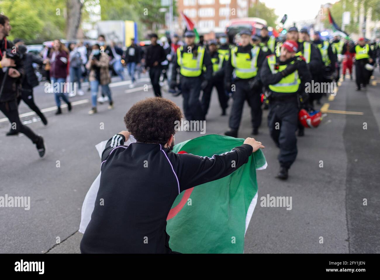 A protester waves an Algerian flag in front of police, Free Palestine Protest, London, 22 May 2021 Stock Photo