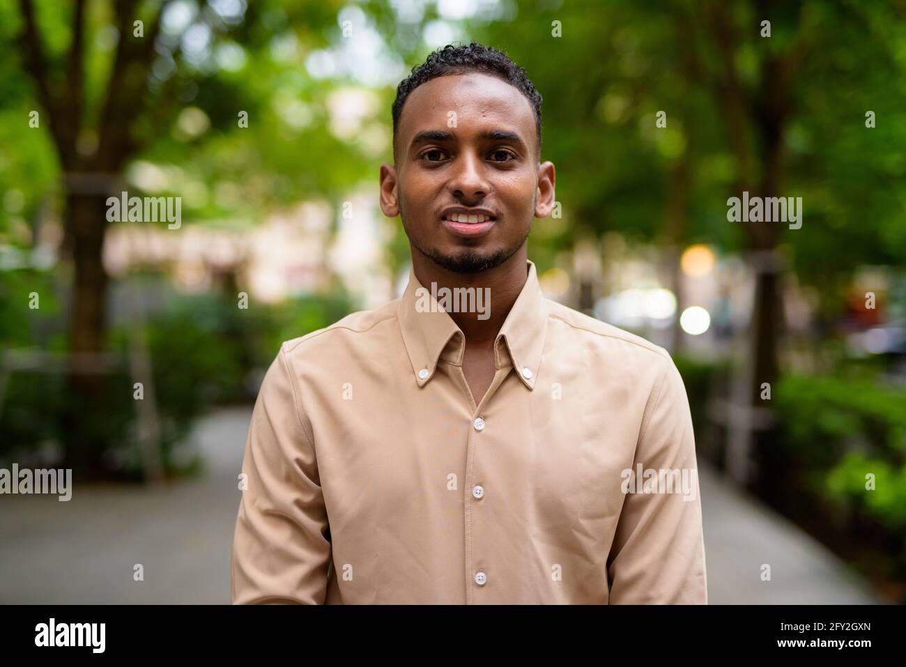 Portrait of handsome black young African businessman outdoors at park Stock Photo