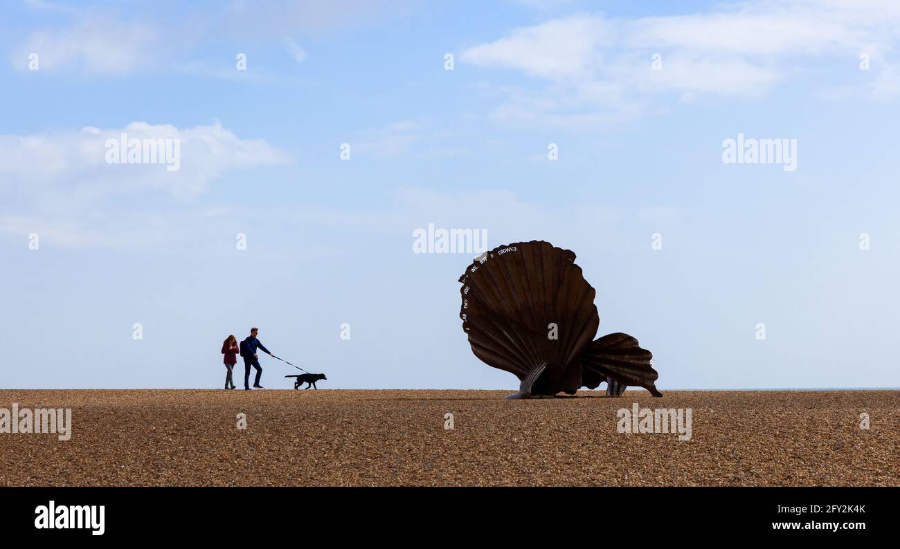 Tourists with their dog walking by the Scallop sculpture on the beach in Aldeburgh, Suffolk. UK. Stock Photo