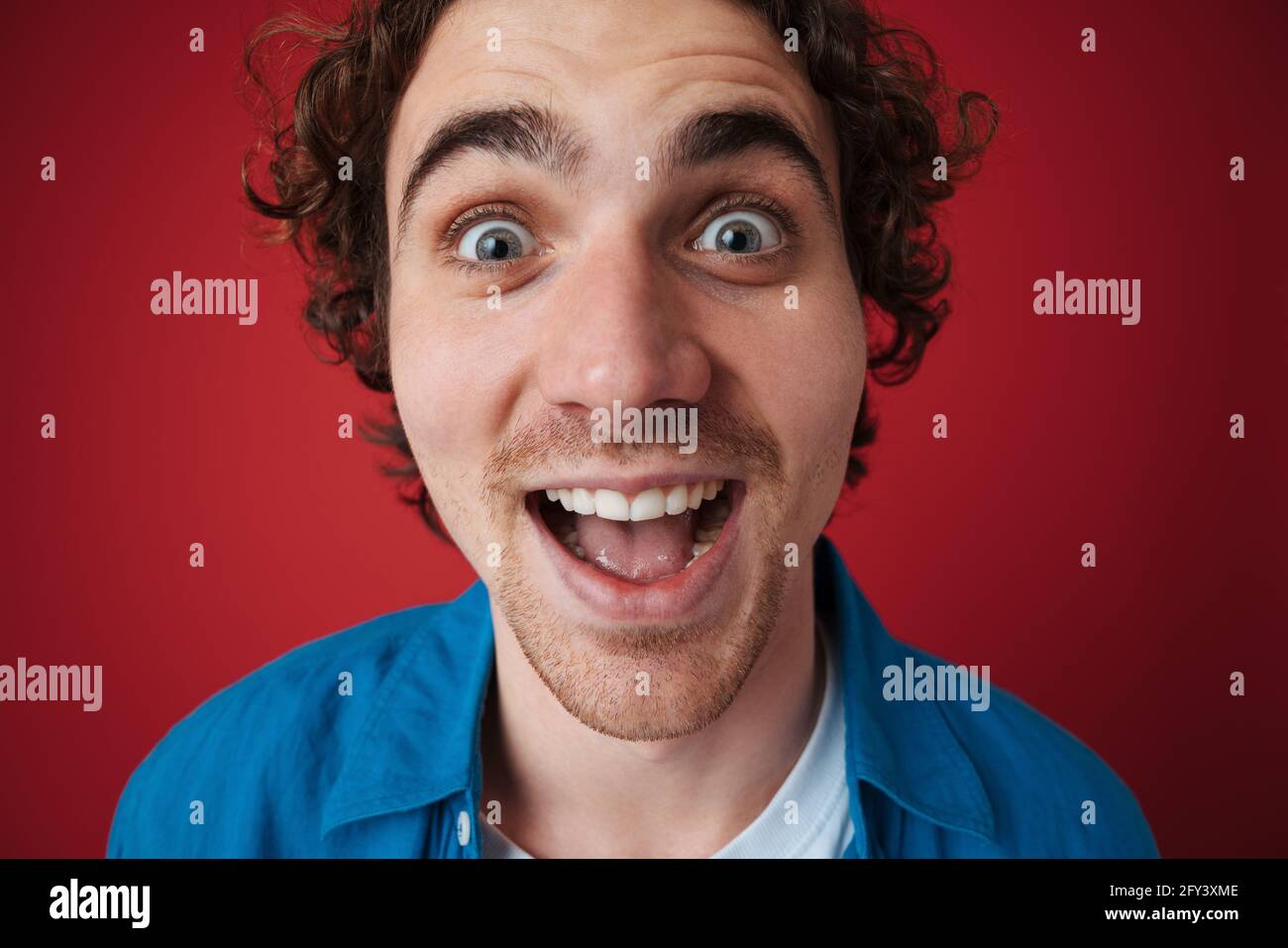 Excited handsome man expressing surprise on camera isolated over red ...