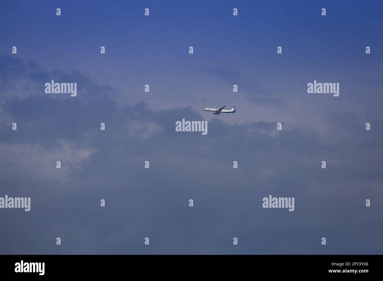Propeller plane lit by the sun against a blue sky with white clouds and ...