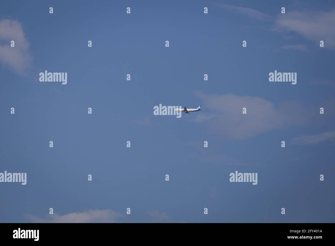 Propeller plane lit by the sun against a blue sky with white clouds and ...