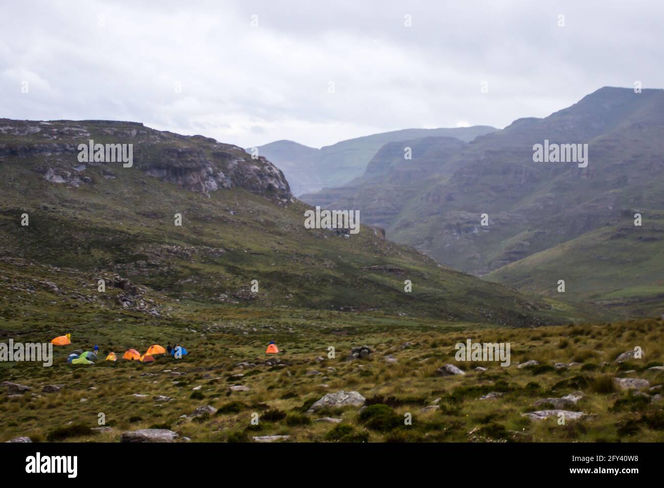 A group of brightly colored hikers tents in a remote part of the Upper Drakensberg Mountains on the border between South Africa and Lesotho. The quick Stock Photo