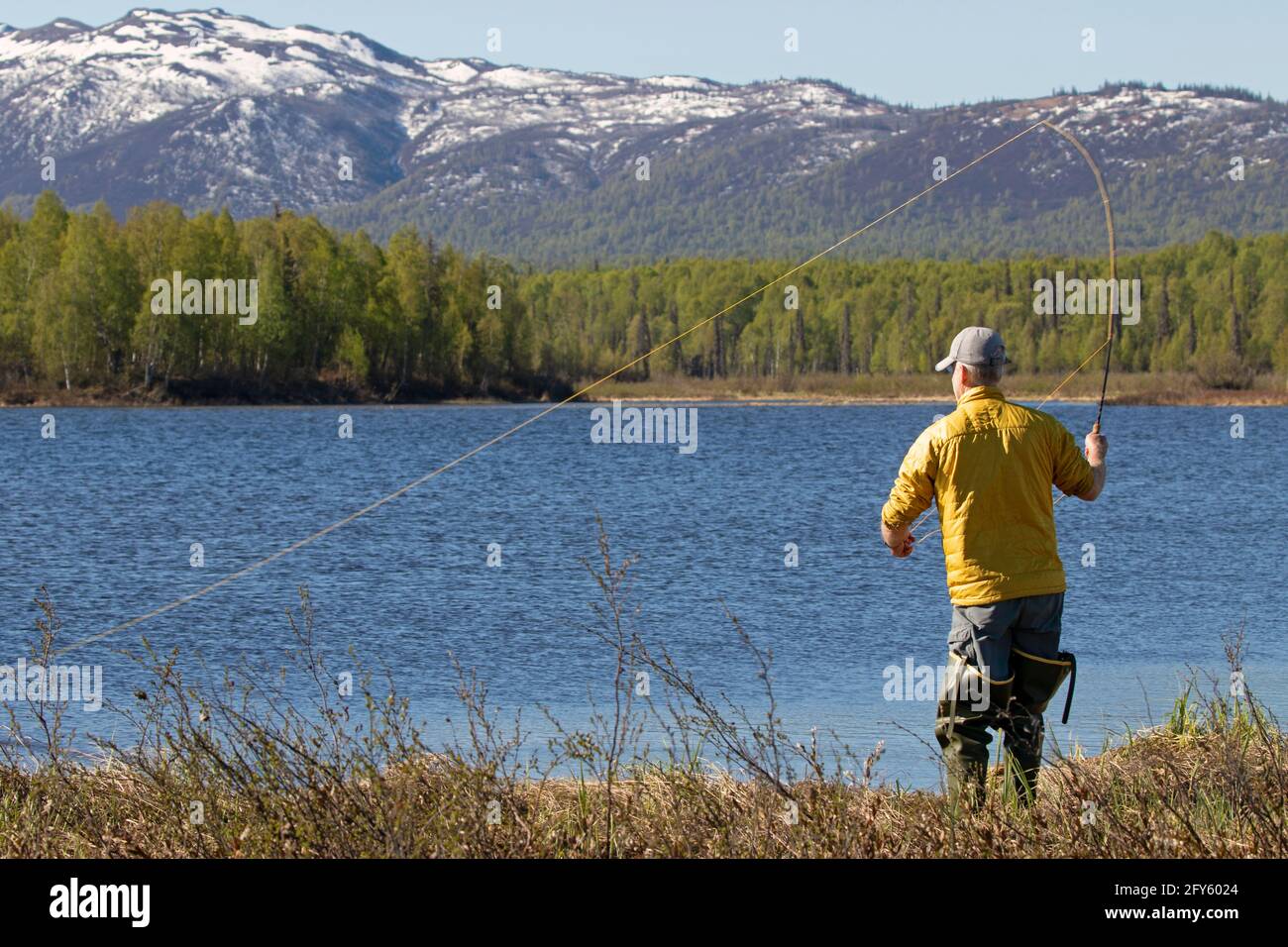 An angler casts for northern pike and rainbow trout on a remote lake in Southcentral Alaska's Susitna Valley. Stock Photo