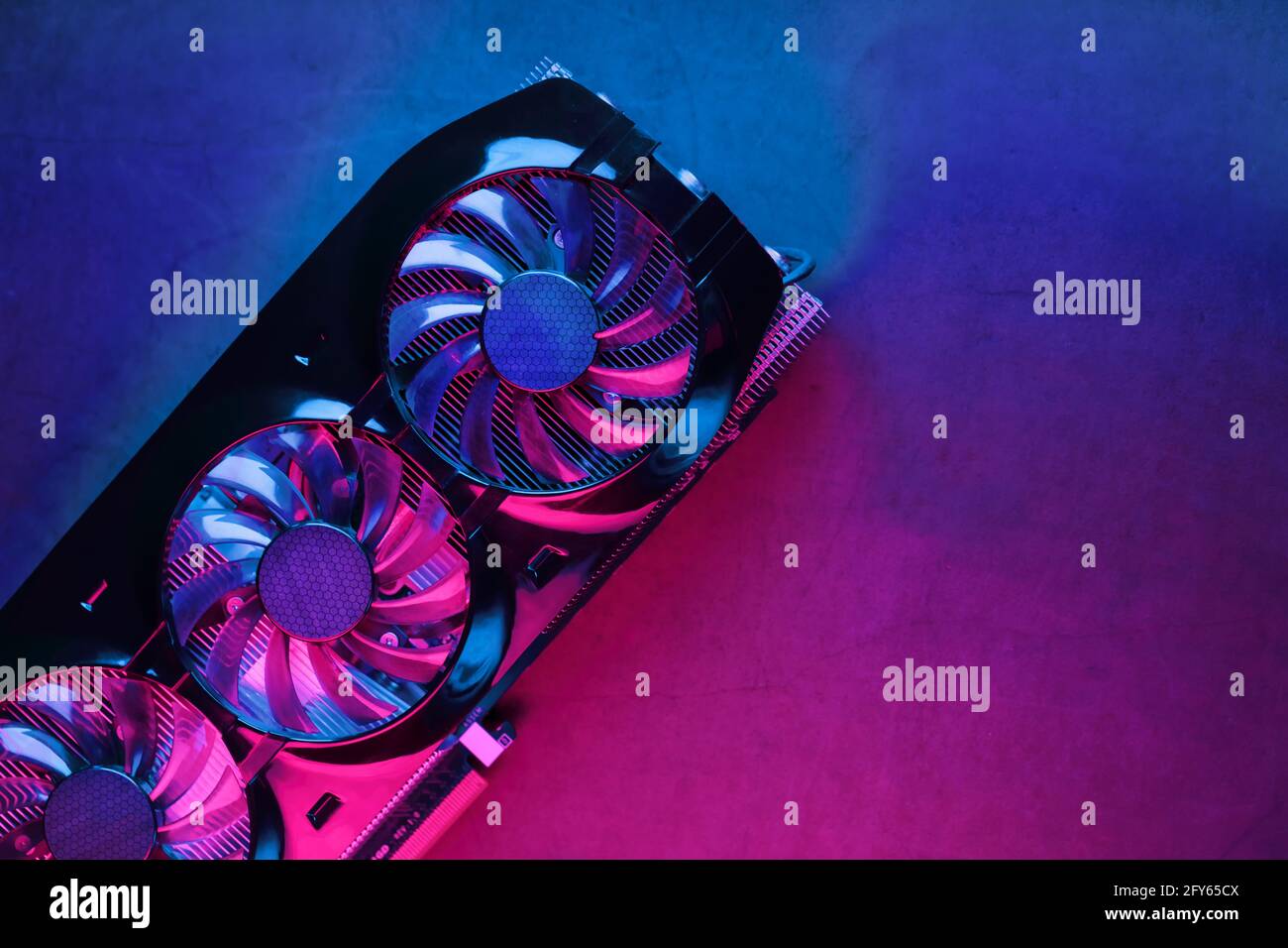Gaming graphics card with neon magenta-cyan illumination and high-speed fans. Video chip for mining and powerful games in the cyberpunk concept. Stock Photo