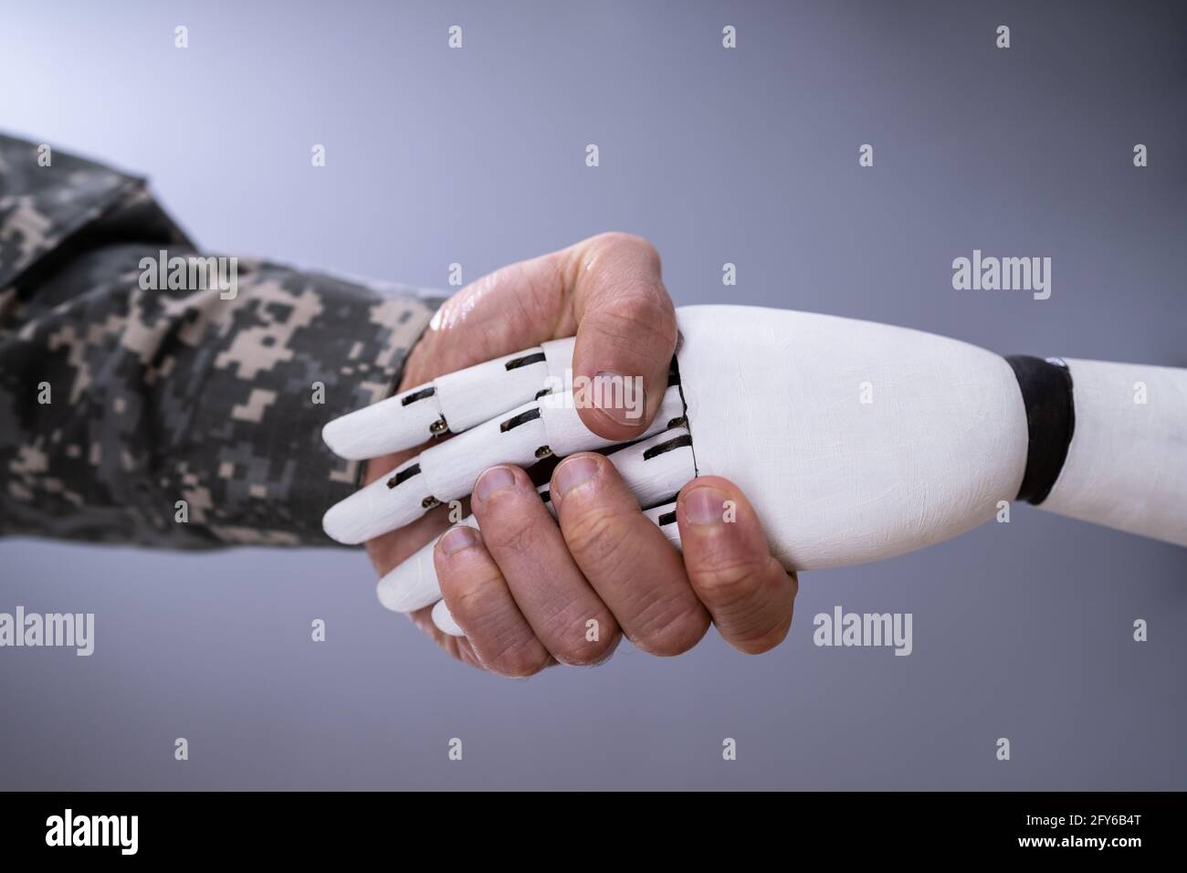 Robot AI Hand Handshake With Military Solider Stock Photo