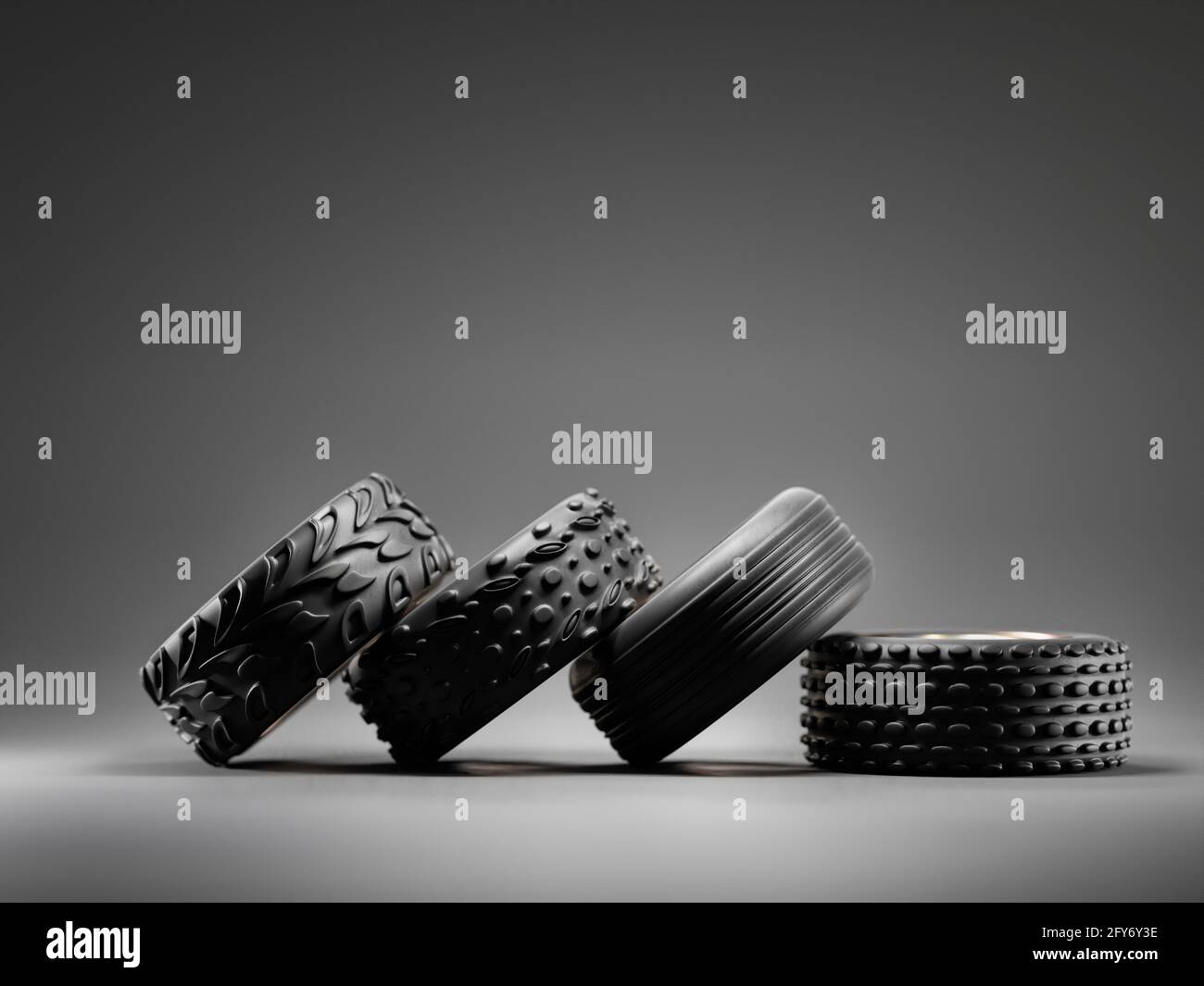 3D rendering of four car tyres each with different tread type on dark gray background Stock Photo
