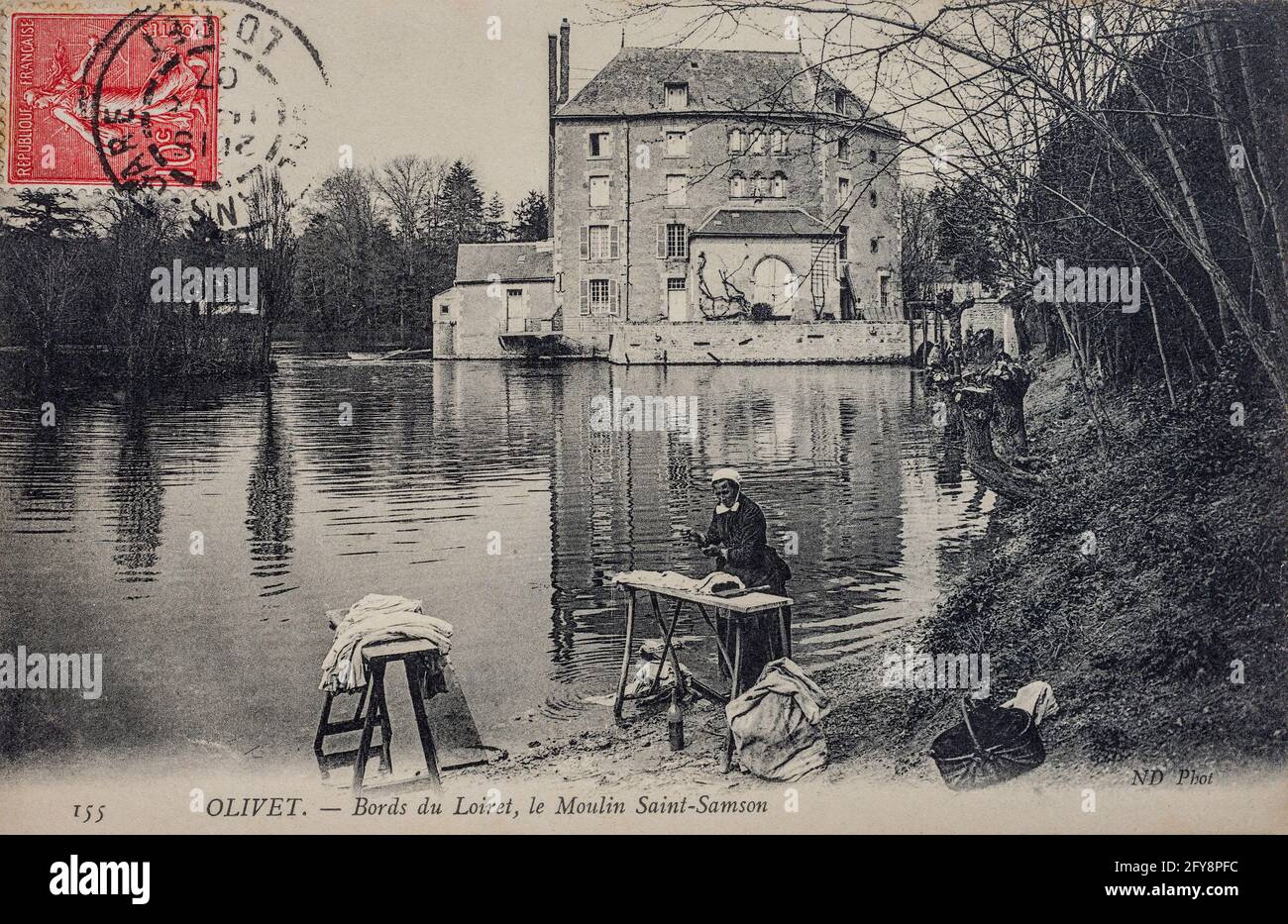 1907 French postcard depicting a woman washing clothing on the bank of the river Loiret, France. Stock Photo