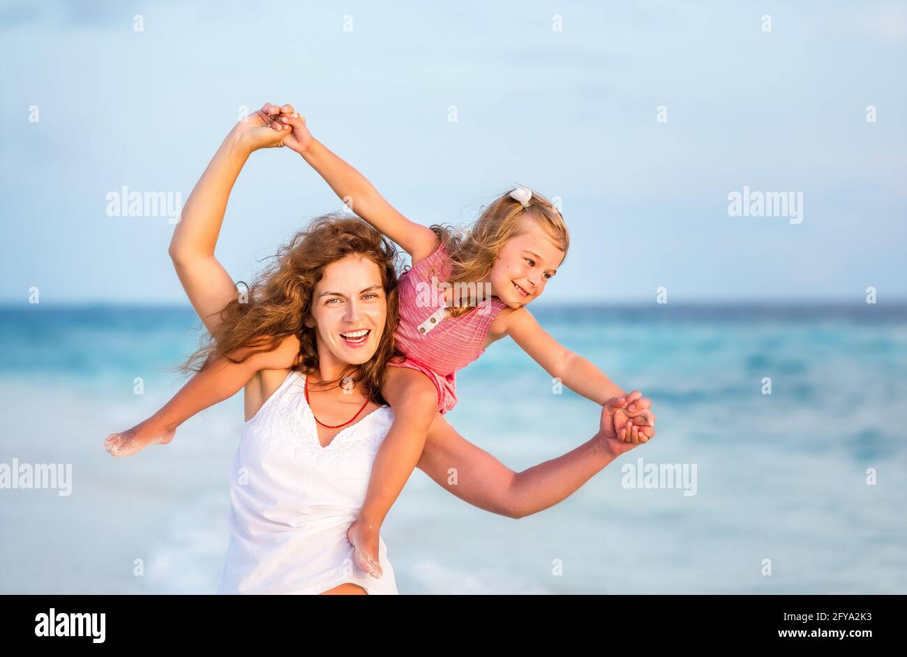 Happy mother and little daughter having fun on beach on Maldives at summer vacation. Family on the beach concept. Stock Photo