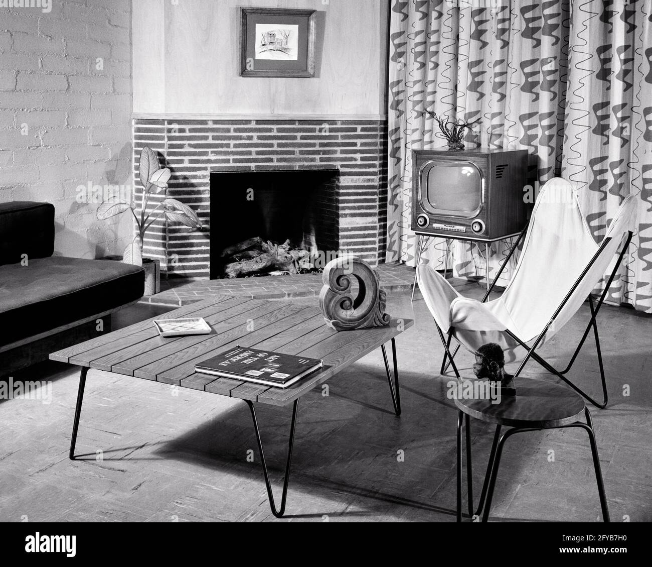 1940s 1950s 1960s LIVING ROOM COFFEE TABLE COUCH BRICK FIREPLACE TELEVISION FABRIC DRAPES A KNOLL HARDOY BKF BUTTERFLY CHAIR - asp ap12608 ASP001 HARS DRAPES INNOVATION CONNECTION STILL LIFE INTERIOR DESIGN POPULAR STYLISH FURNISHING COOPERATION CREATIVITY GRAPHIC DESIGN HOME DECOR KNOLL URBAN DEVELOPMENT BLACK AND WHITE FURNISHINGS OLD FASHIONED Stock Photo