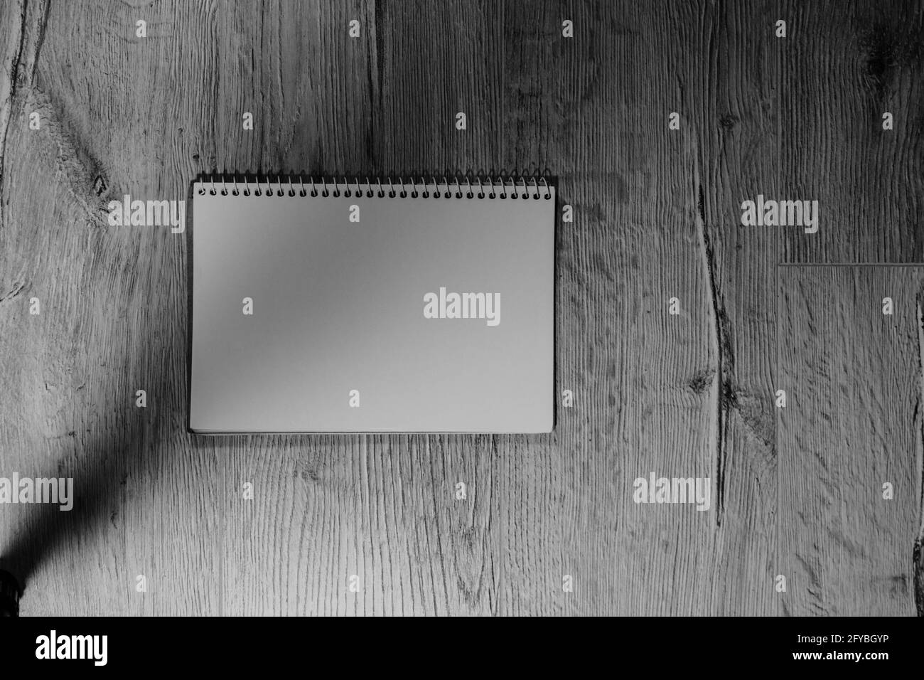 The notebook is located horizontally on a wooden background. Black and white photo. Stock Photo