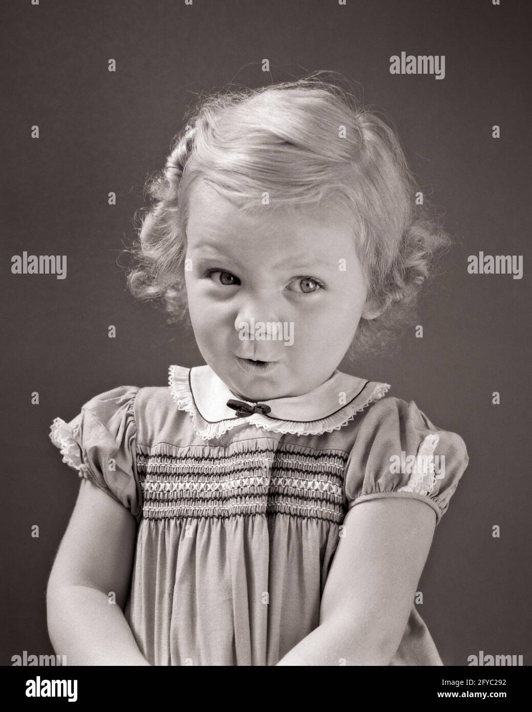 1930s 1940s BLOND TODDLER GIRL LOOKING AT CAMERA UP AND TO THE SIDE SHY BASHFUL FACIAL EXPRESSION WEARING DRESS WITH SMOCKING - j3100 HAR001 HARS HOME LIFE COPY SPACE HALF-LENGTH EXPRESSIONS B&W EYE CONTACT HAPPINESS DISCOVERY AND THE TO UP SHY PLEASANT AGREEABLE CHARMING JUVENILES LOVABLE PLEASING ADORABLE APPEALING BABY GIRL BASHFUL BLACK AND WHITE CAUCASIAN ETHNICITY HAR001 OLD FASHIONED SMOCKING Stock Photo