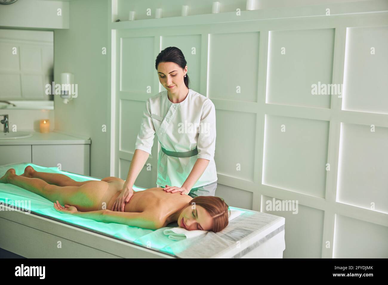 Professional massage therapist massaging back of female client in room  indoors Stock Photo - Alamy