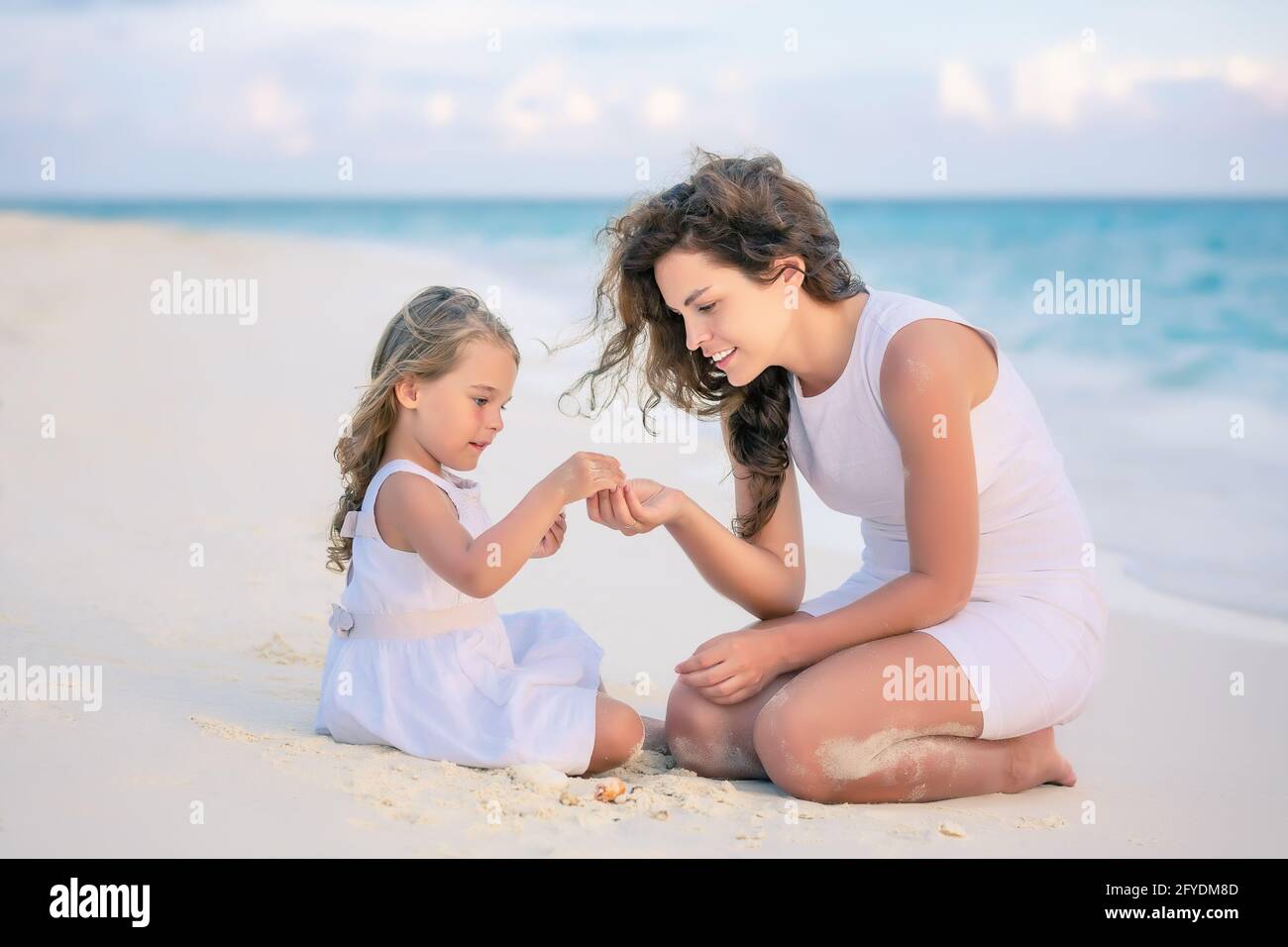 Mother and little daughter playing on the beach on Maldives at summer vacation Stock Photo