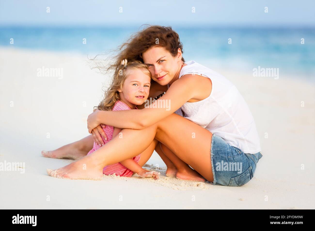 Mother and little daughter resting on the beach on Maldives at summer vacation Stock Photo