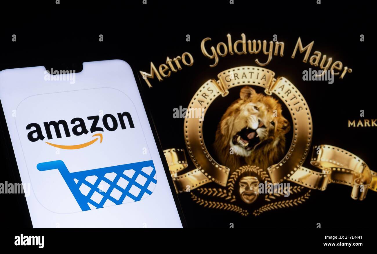 Amazon app logo seen on the smartphone and blurred Metro Goldwyn Mayer logo on the laptop. Stafford, United Kingdom, May 27, 2021. Stock Photo
