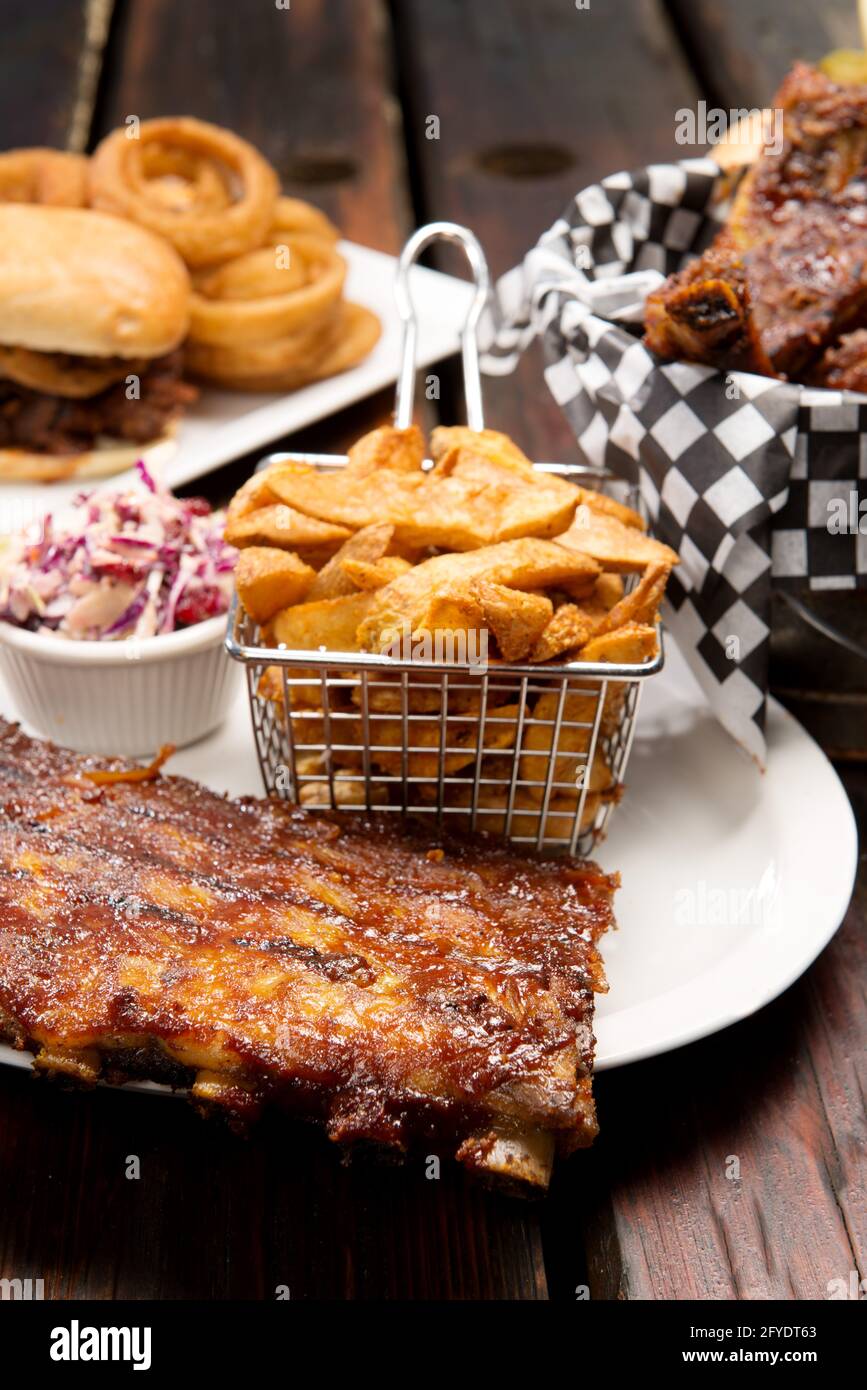 Barbecue restaurant food selection.  Barbecued pork ribs, beef ribs, pulled pork sandwich, and beef dip with home cut french fries. Stock Photo