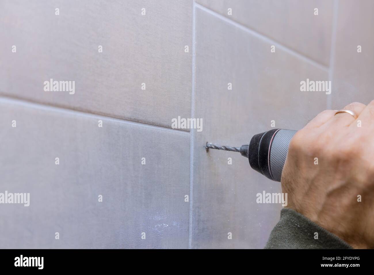 Carpenter in work on drilling hole in bathroom wall for installing