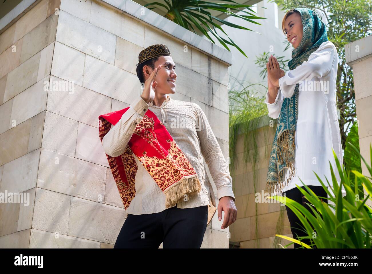 Asian Muslim man going to work leaving housewife woman wearing traditional dress Stock Photo