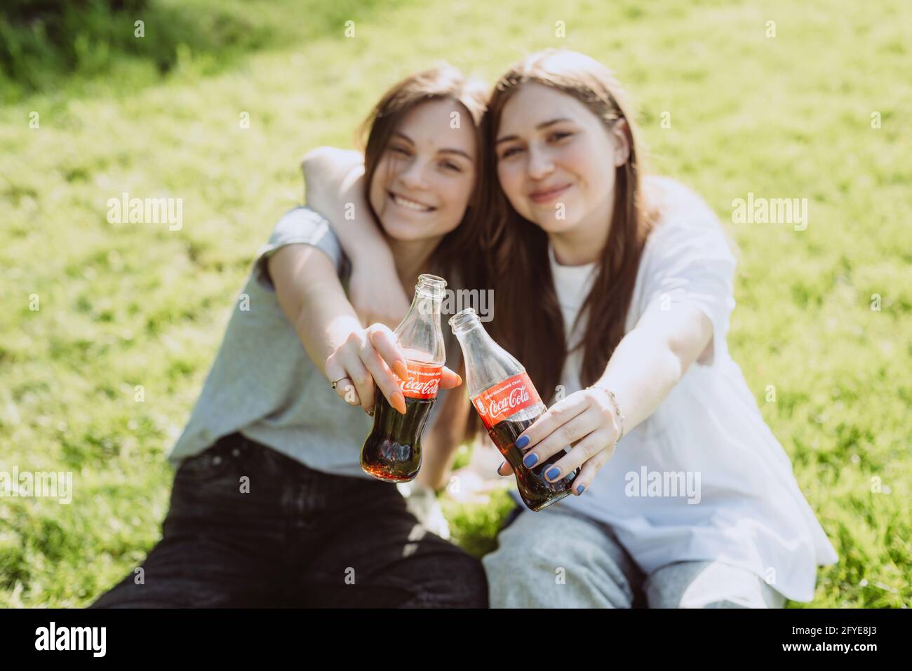 Bucha, Ukraine, May 26, 2021. Beautiful young women teenagers on a hot summer day with glass bottles of Coca-Cola in their hands, smiling happy. Soft Stock Photo