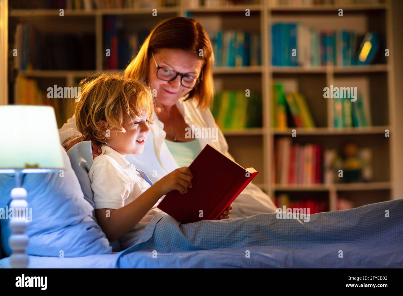 Child reading book in bed. Kids read at night. Little boy and mother