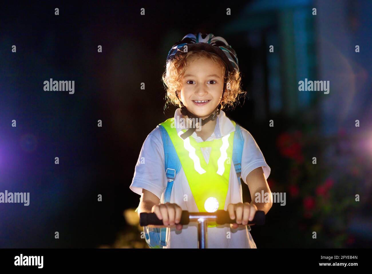 Kid in reflective vest in darkness. Safety on dark city streets for school children. Safe way home at night or in the evening. Stock Photo