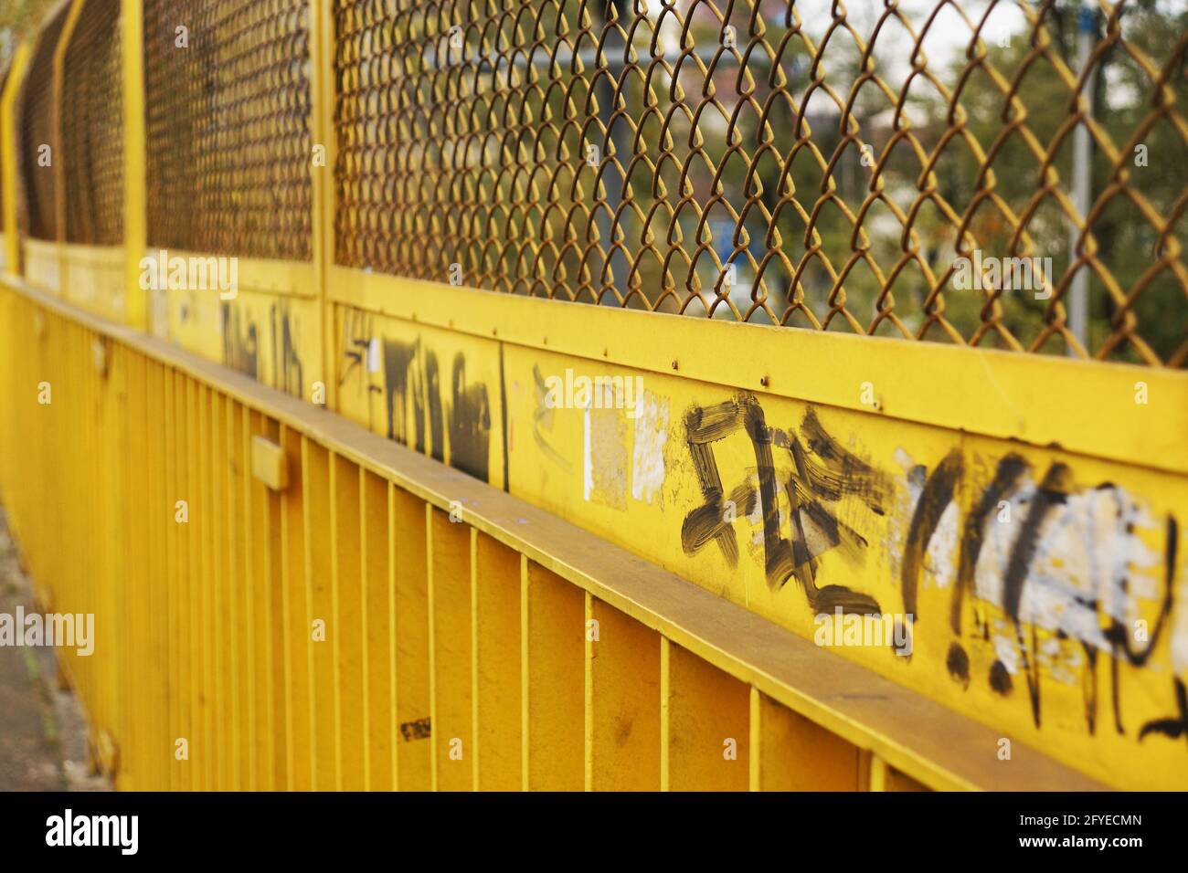 POZNAN, POLAND - Nov 01, 2012: A yellow metal fence with some sprayed words Stock Photo
