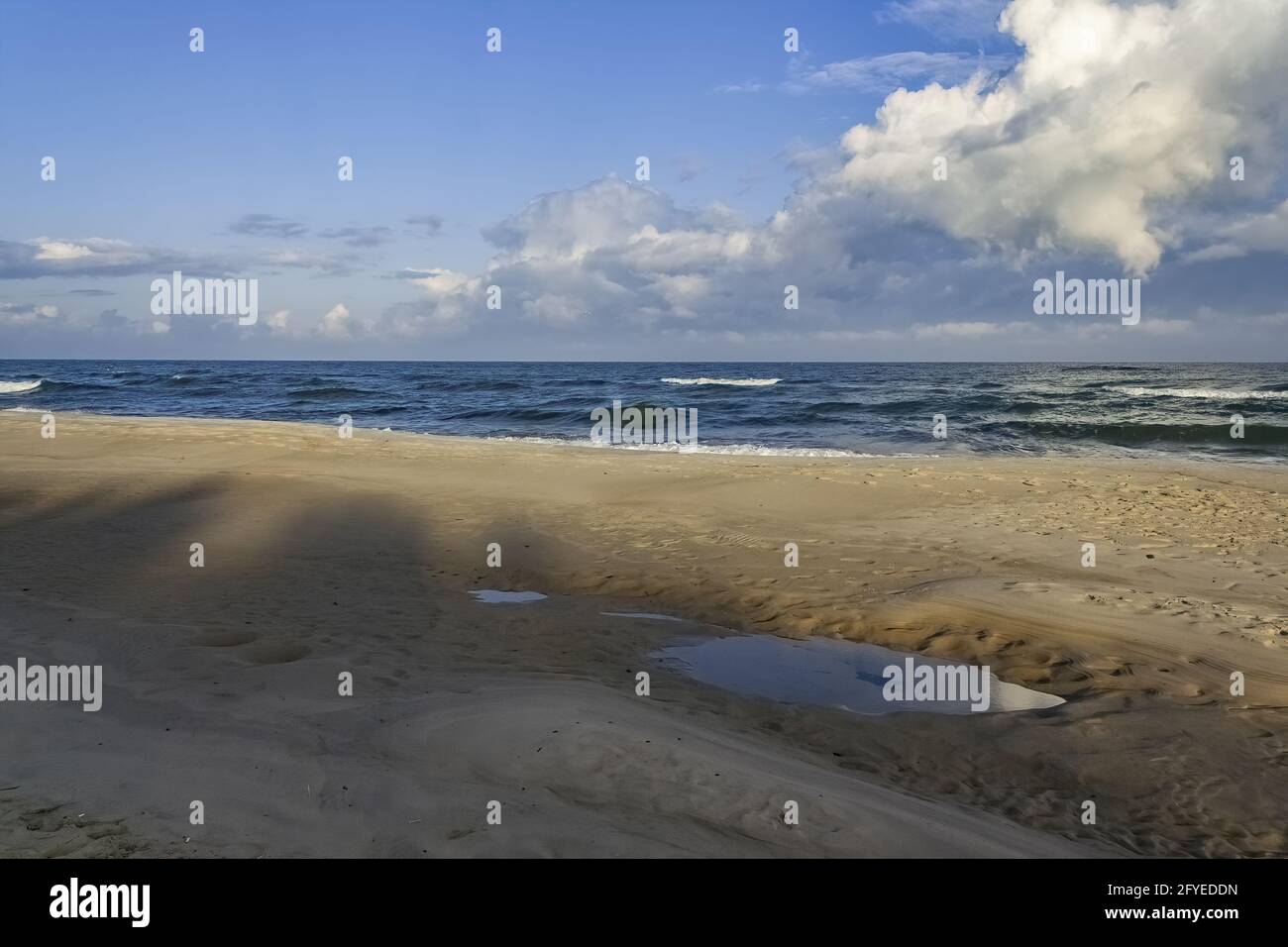 Sandy beach and wavy sea under cloudy sky Stock Photo - Alamy