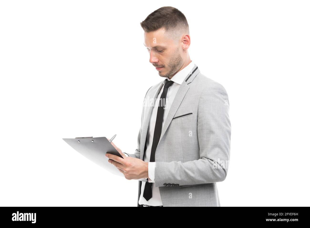 Horizontal medium portrait of handsome young adult Caucasian man wearing gray suit holding clipboard making notes, white background Stock Photo