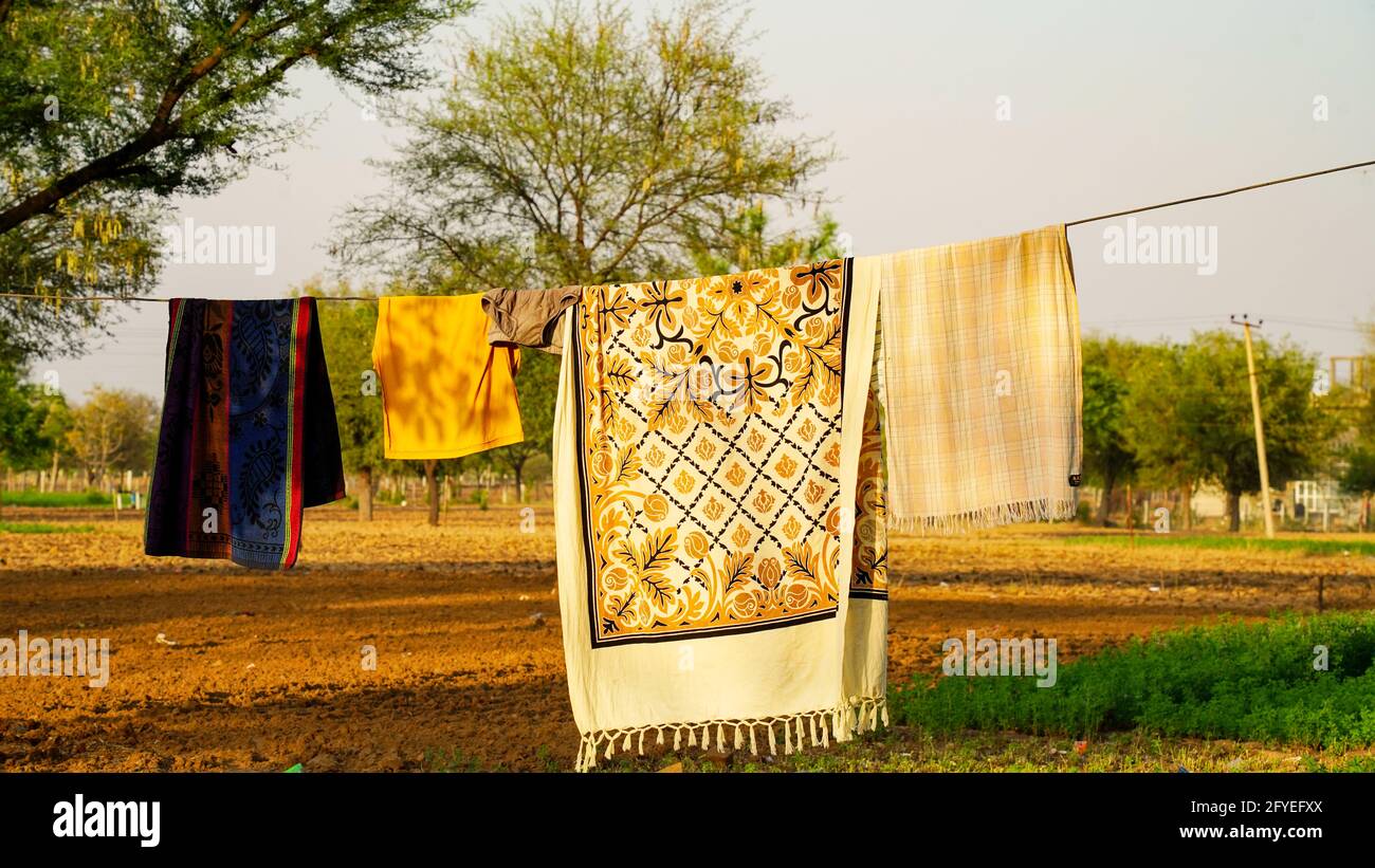 Colourful clean sheets outdoors. Drying on a rope on background of beautiful scenery in the garden. Stock Photo