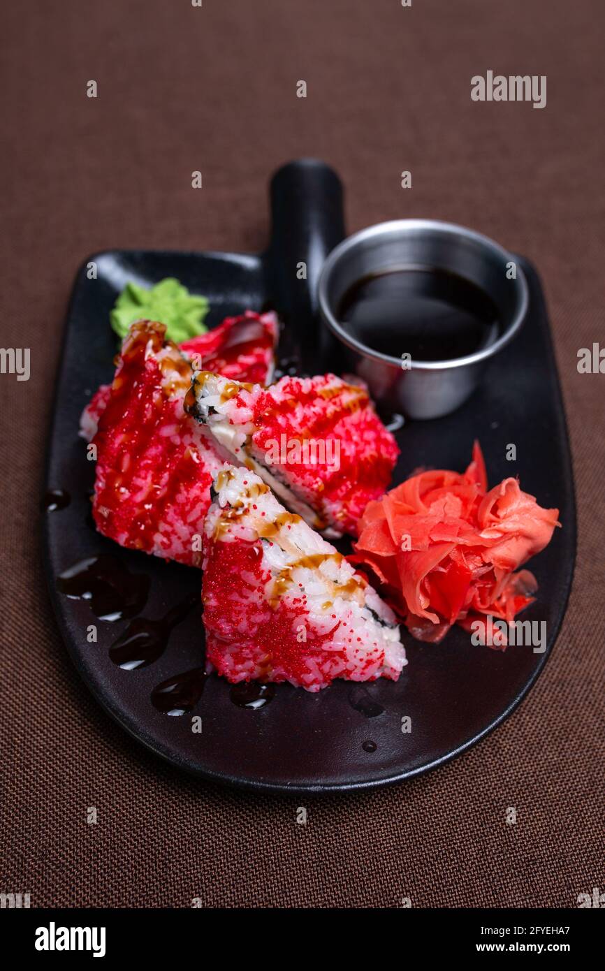 Red rice with fish, wasabi and ginger on a black plate Stock Photo
